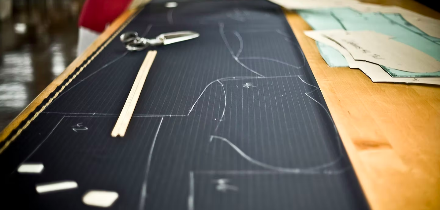 Oxxford cutting room table with tailoring tools and garment pieces